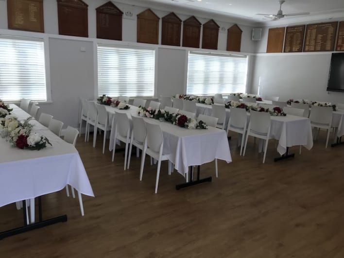 A room with tables and chairs set up for a wedding.