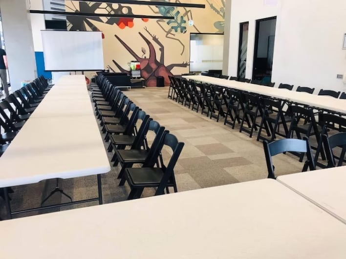 A room full of tables and chairs with a mural on the wall.