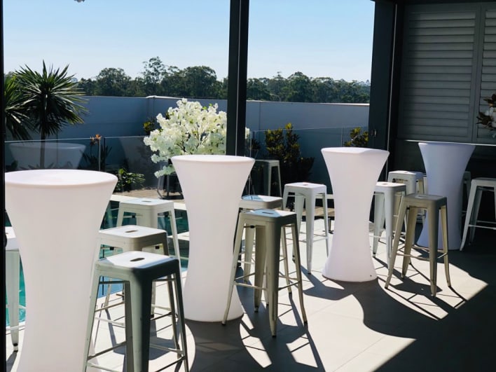 A group of white stools in front of a pool.