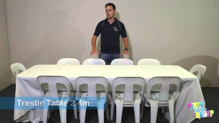 A man standing in front of a table with white chairs.