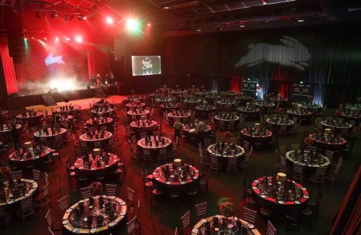 A large room with tables and chairs set up for an event.