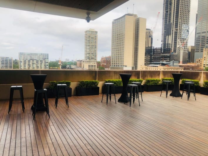 A rooftop bar with tables and chairs overlooking a city.