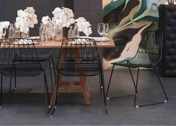 A dining table with black chairs and a painting on the wall.