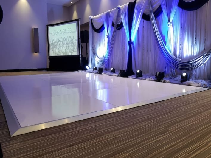 A white dance floor with blue and white drapes.