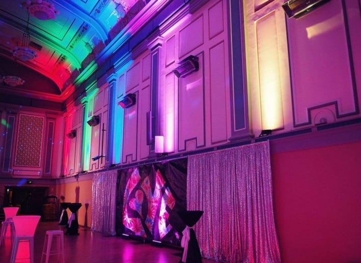 A large hall with colorful lights and a dance floor.