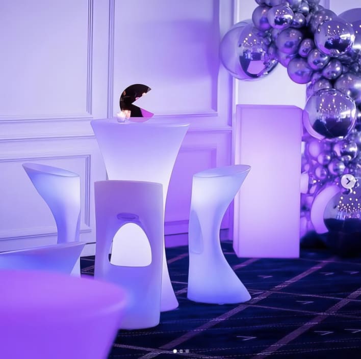 A purple table and chairs in a room with purple balloons.