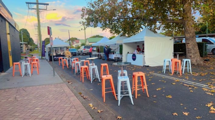 A street market with orange stools and tents.