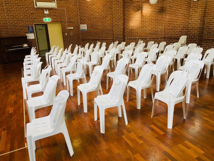 A large room full of white chairs and a piano.