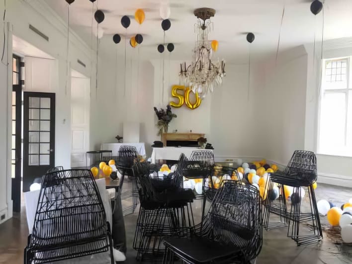 A room filled with black and yellow chairs and balloons.