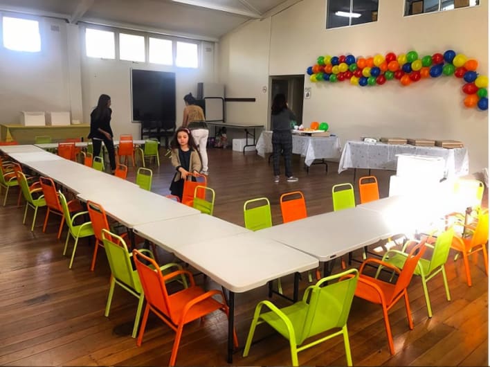 A large room filled with tables and chairs and balloons.