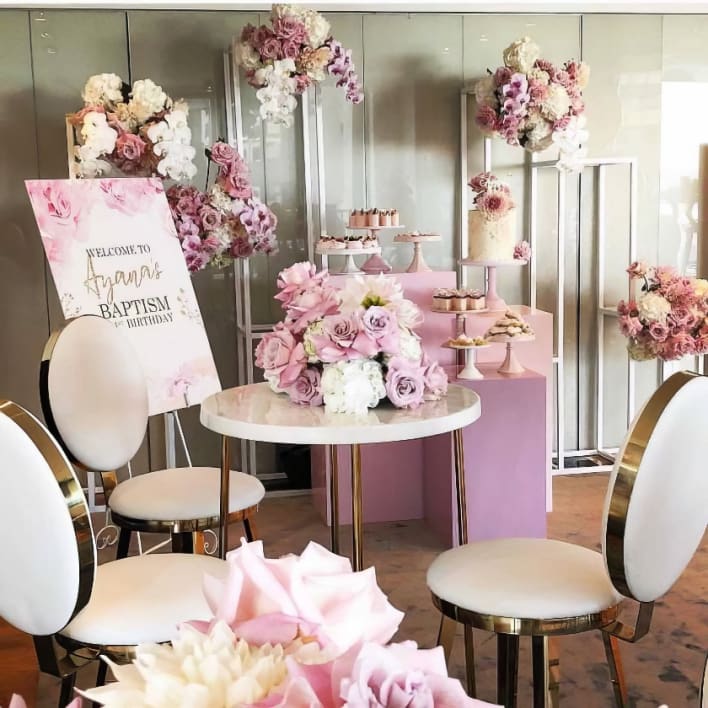 A pink and white table setting with chairs and flowers.