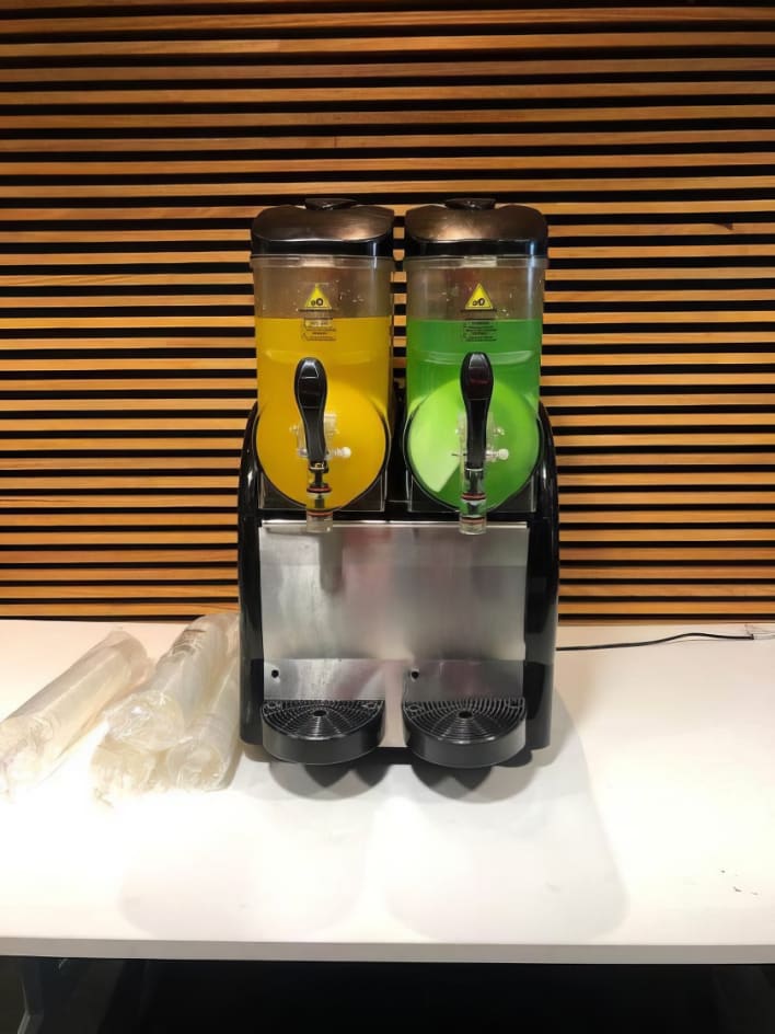 Two juice dispensers on a table next to each other.