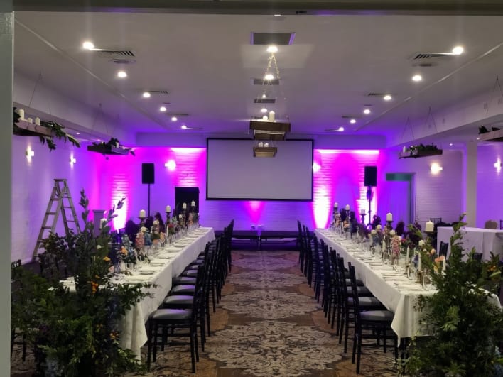 A room with tables and chairs set up with purple lighting.