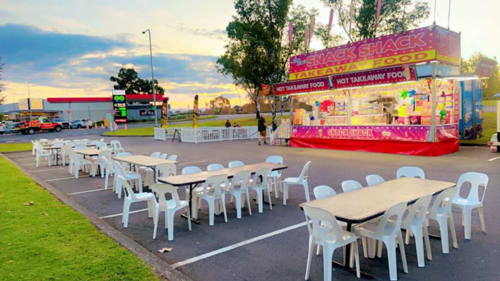 A white table and chairs are set up in a parking lot.