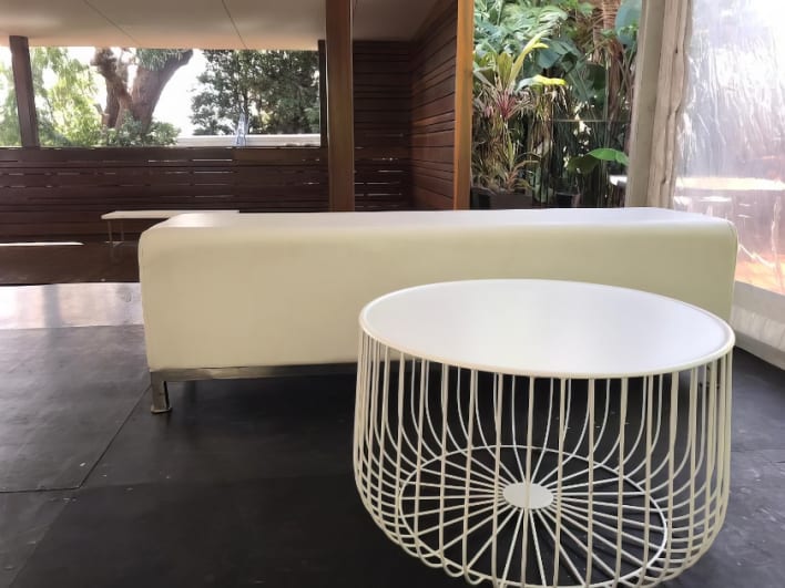 A white coffee table with a wire basket on it.