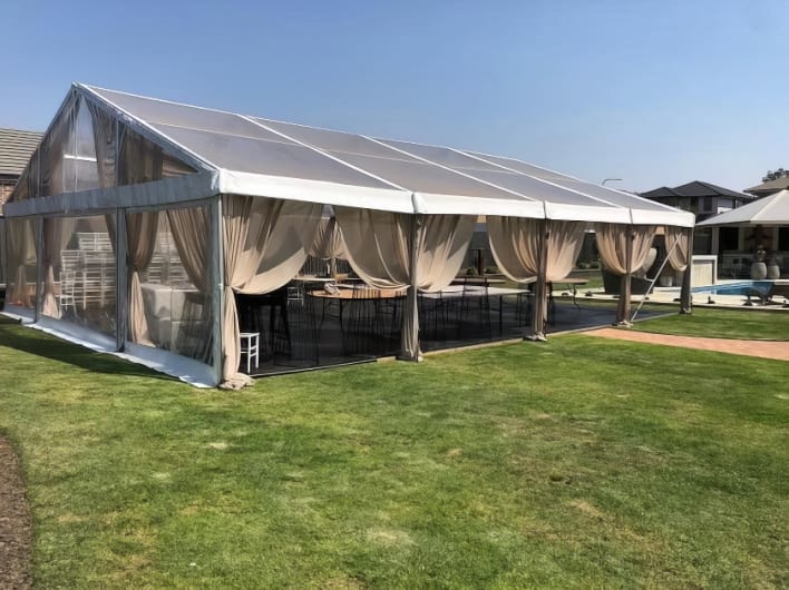 A large tent with curtains on a grassy yard.