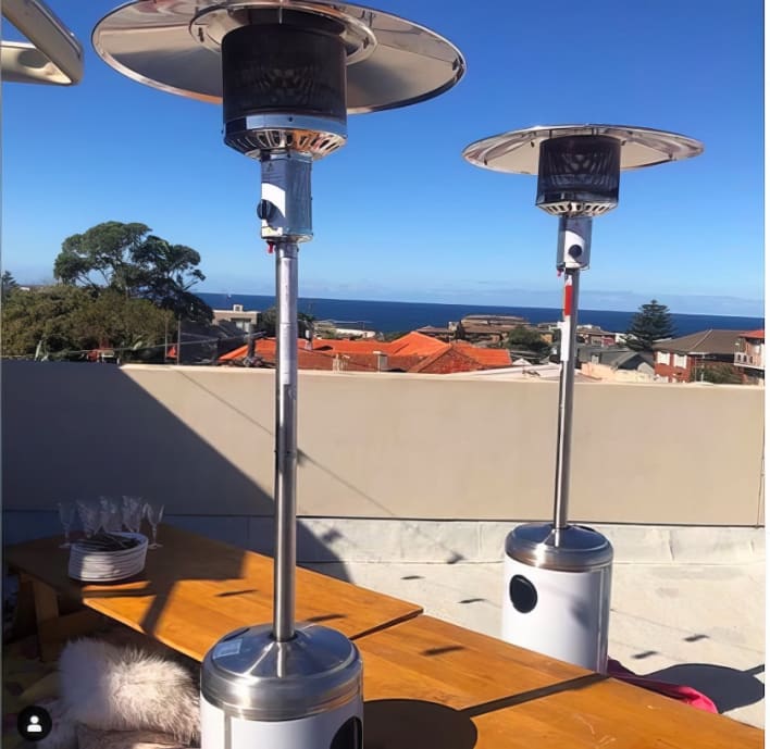 Two patio heaters on top of a table with a view of the ocean.