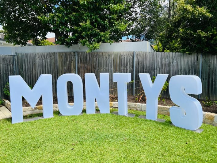 Monty's sign in front of a fence.