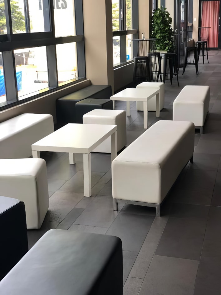 A group of white couches and tables in a lobby.