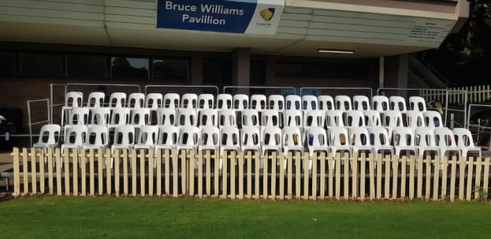 A row of white chairs in front of a building.