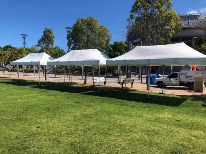 A group of white tents set up in a grassy area.