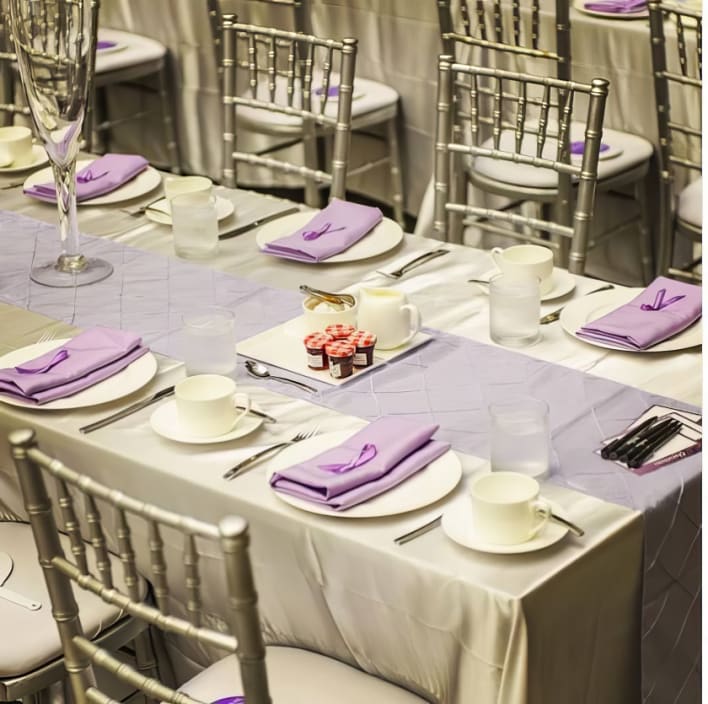 A silver table setting with purple napkins and silver plates.