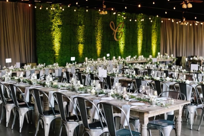 A wedding reception set up with tables and greenery.