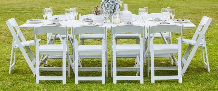 A white folding table set up on a grassy field.
