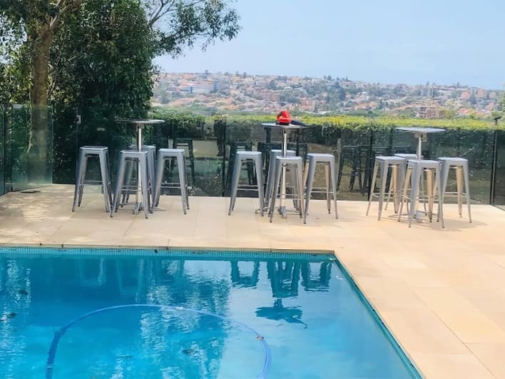 A pool with stools and a view of the city.