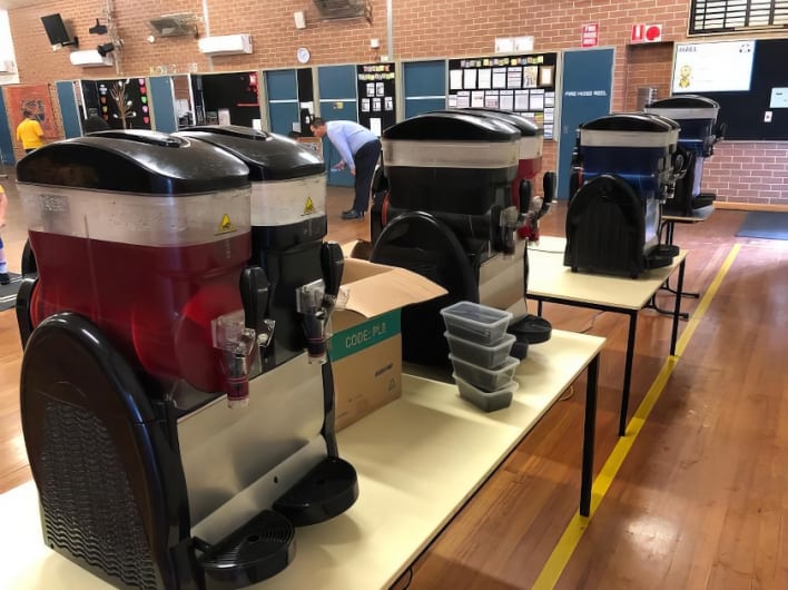 A group of ice cream machines on a table in a school.