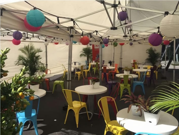 A brightly colored tent with tables and chairs.