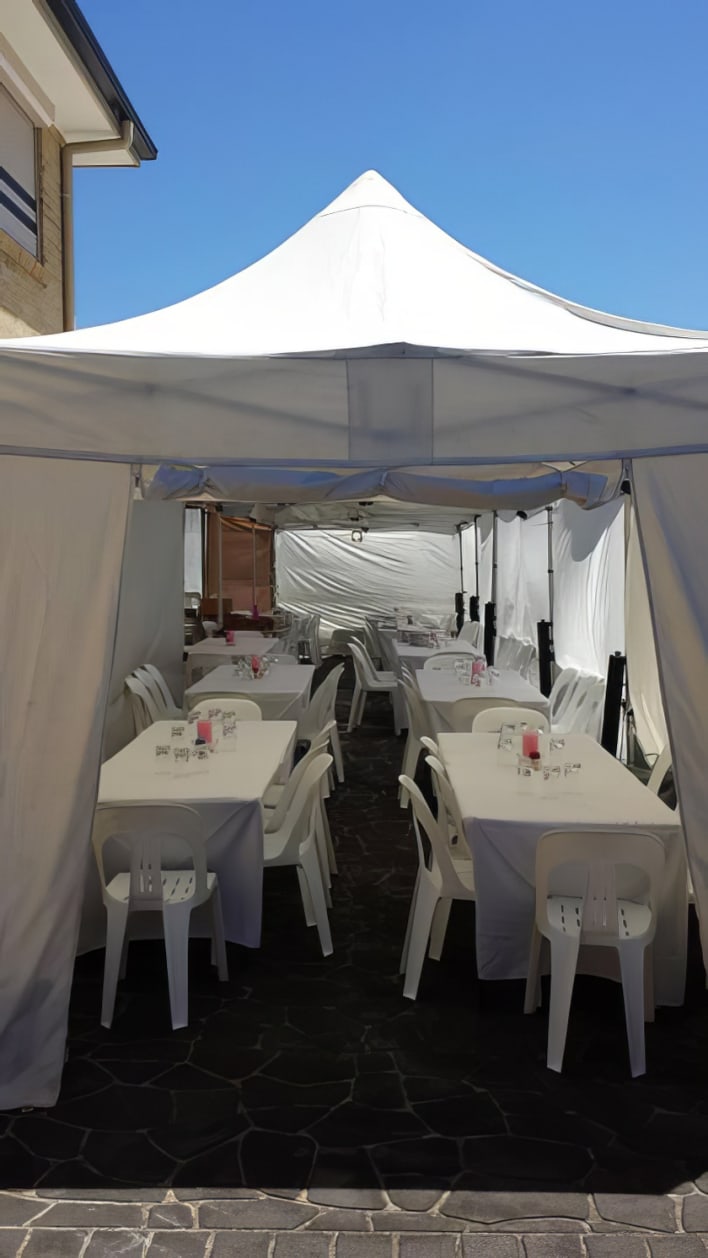 A white tent with tables and chairs set up outside.