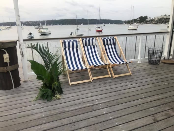 Three deck chairs on a deck overlooking the water.