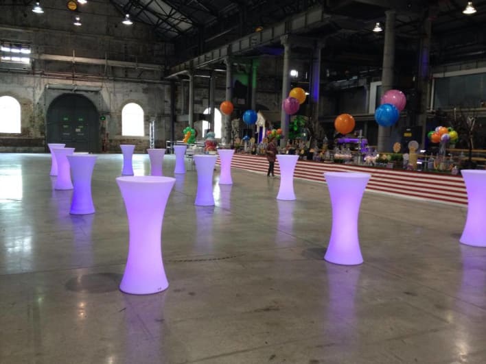 Led bar tables in a warehouse with balloons.