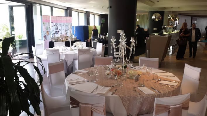 A room with tables and chairs set up for a wedding.