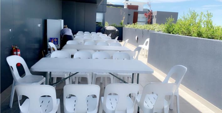A white table and chairs are set up on a balcony.