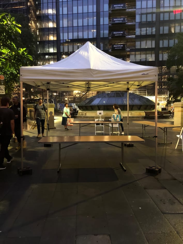A white tent with tables and chairs in the middle of a city.
