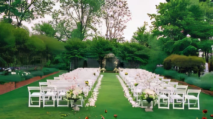 An outdoor wedding ceremony set up with white chairs and green grass.