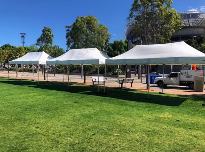 A group of white tents set up in a grassy area.