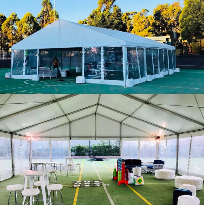 A white tent with tables and chairs on a tennis court.