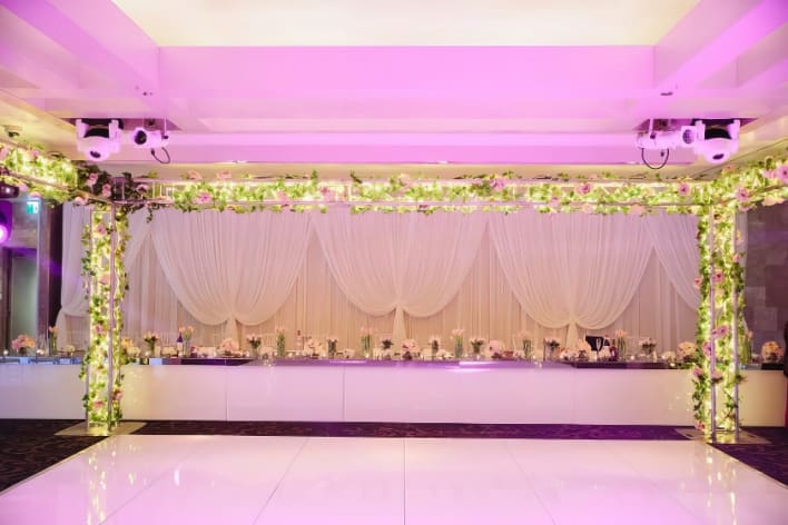 A wedding reception in a white room with purple lighting.