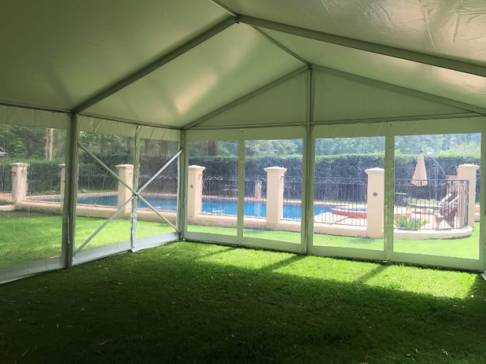 A white tent in a backyard with a pool.