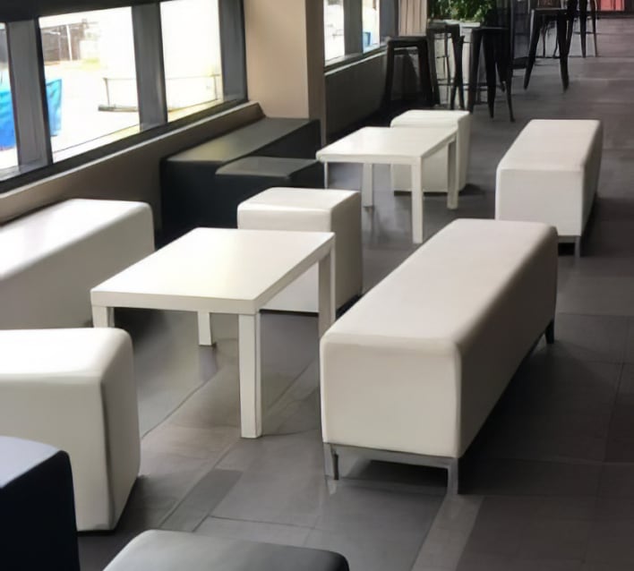 A group of white couches and tables in a lobby.