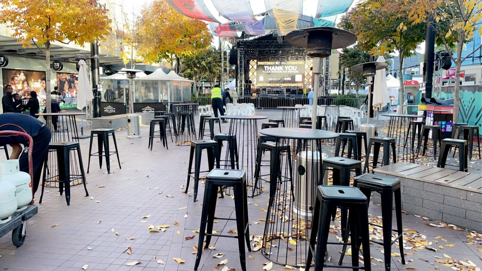 A group of black stools on a sidewalk in a city.