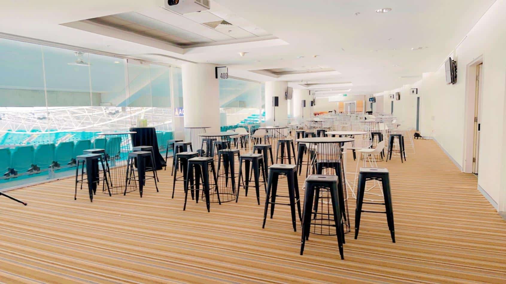 A spacious room adorned with an assortment of tables and chairs, including sleek black Tolix stool hire options.