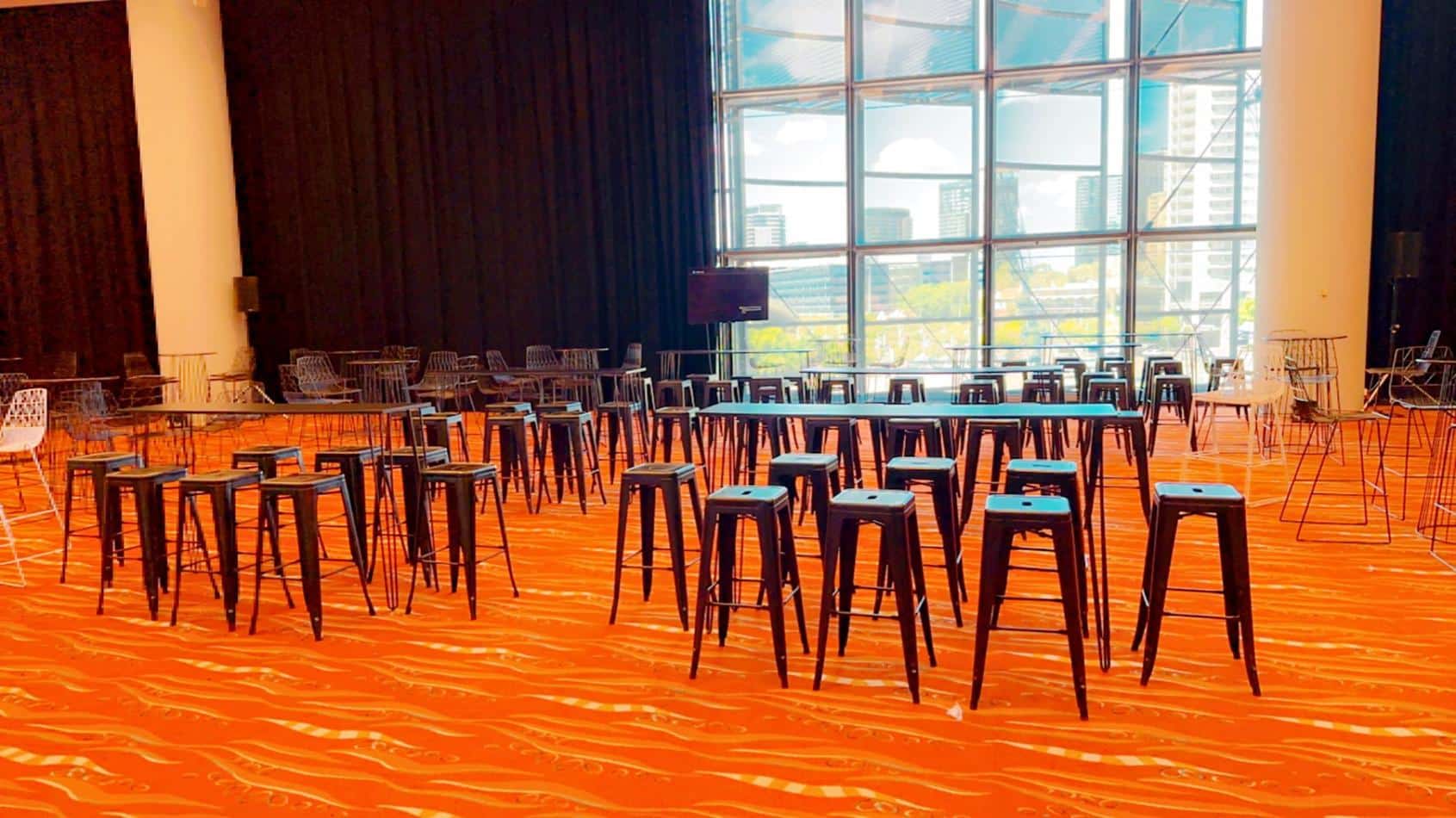 A spacious room filled with numerous tables and chairs, available for Black Tolix Stool hire.