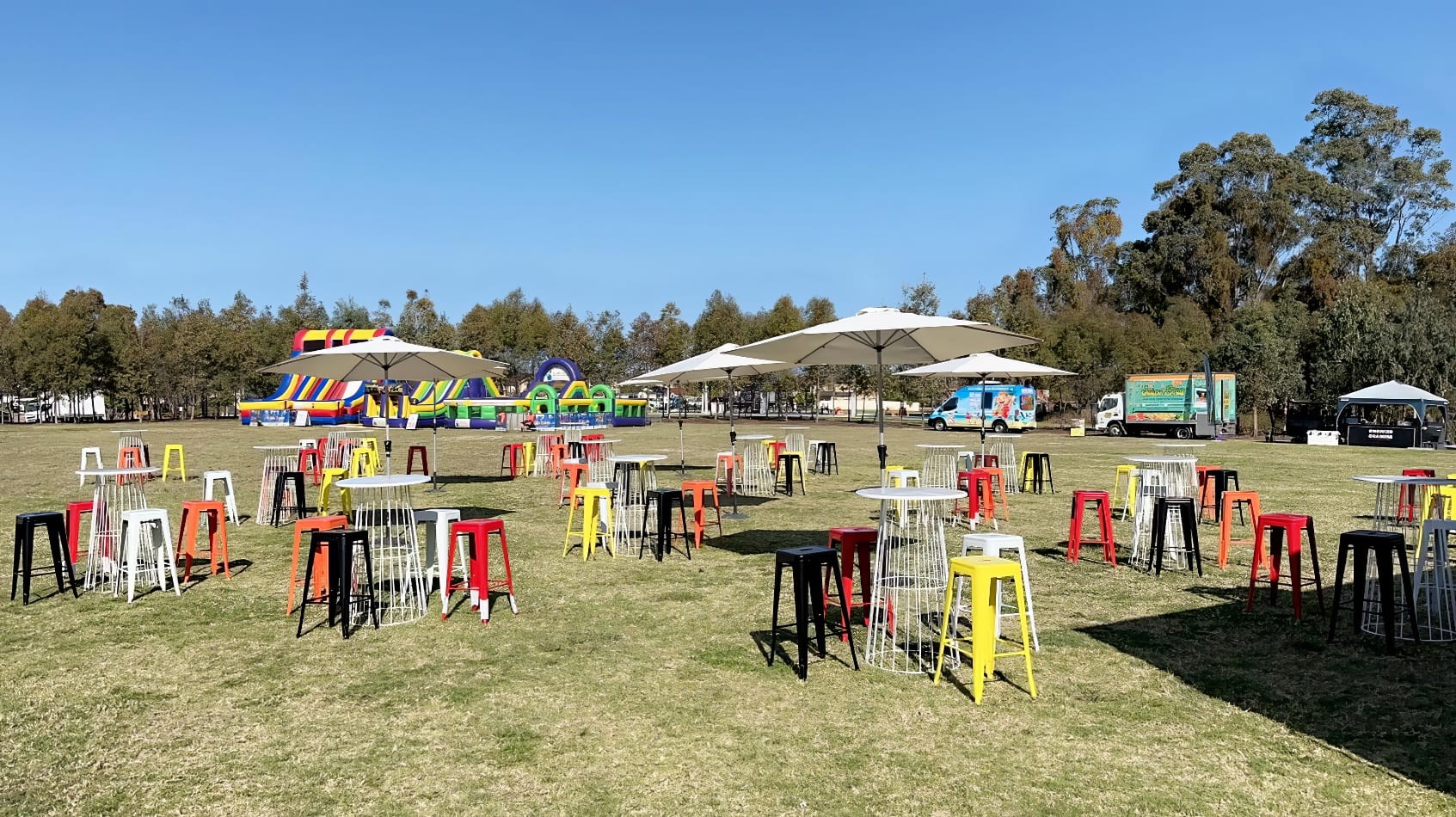 A group of black Tolix stools and chairs set up in a grassy field.