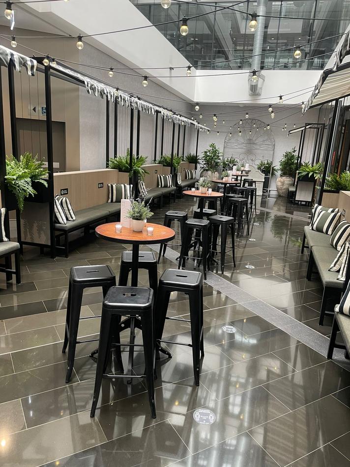 A cafe with tables and chairs, including black Tolix stool hire, in an office building.