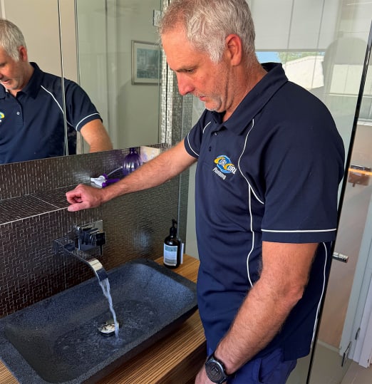 Shane from Curl Curl Plumbing inspecting a bathroom tap