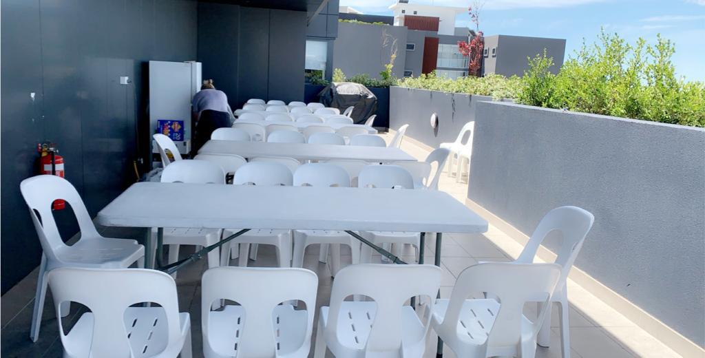 A plastic table and chairs are set up on a balcony.